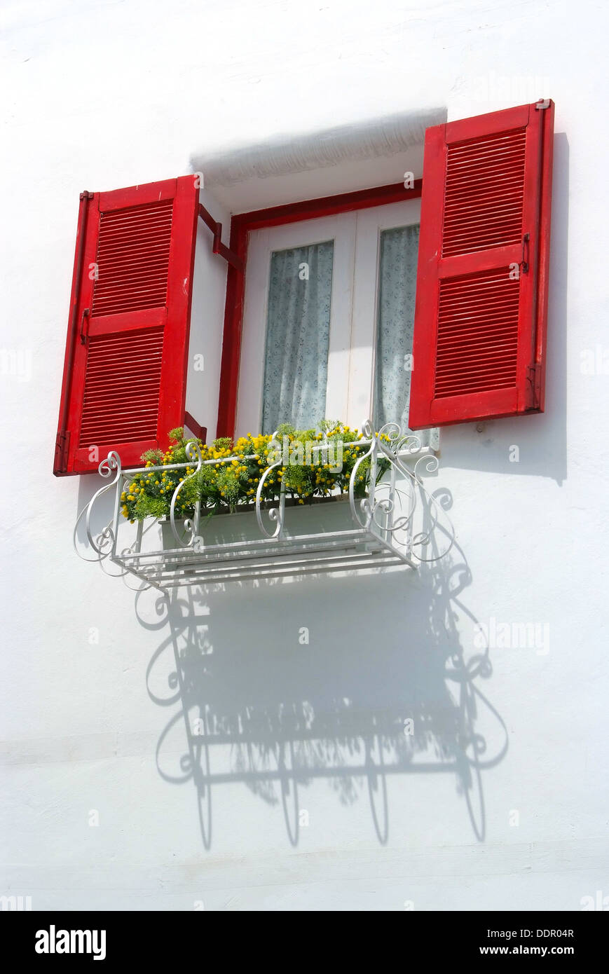Vintage finestra rossa sul muro bianco e cesto di fiori. Foto Stock