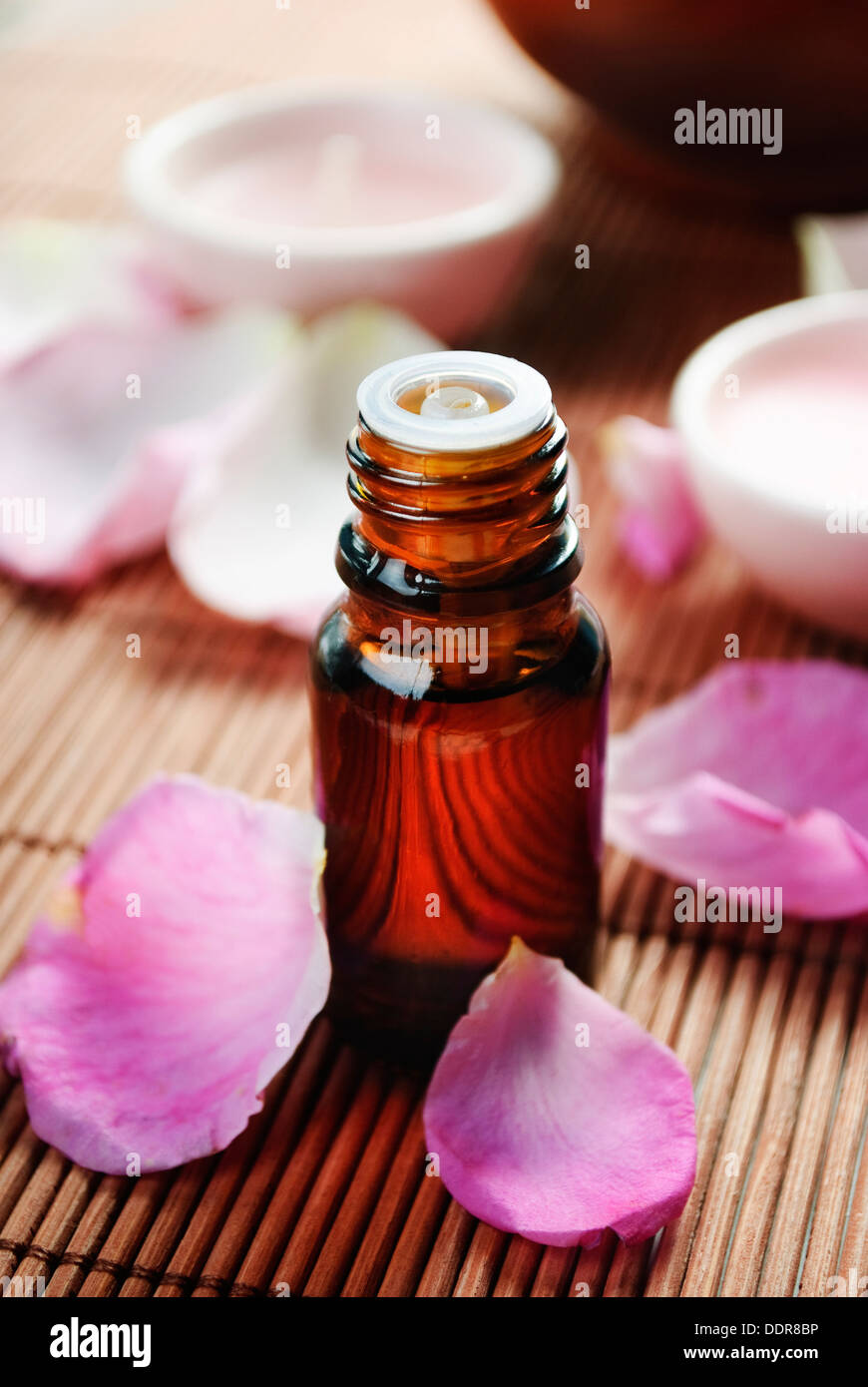 Olio essenziale di petali di rosa su sfondo di legno Foto Stock