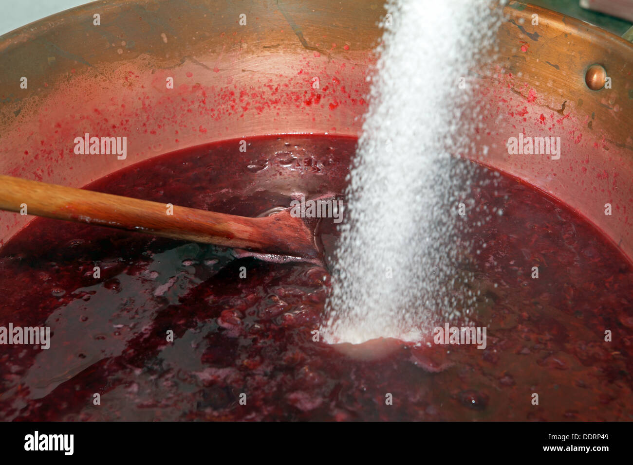 La conservazione di zucchero viene versata in una padella con frutto per la realizzazione di marmellate Foto Stock