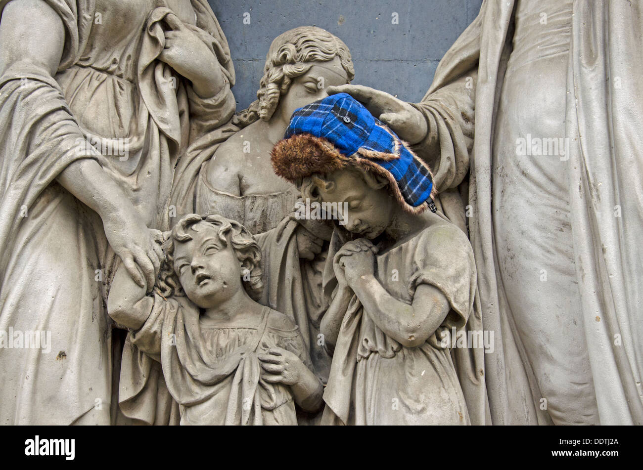 Un cacciatori hat è stato aggiunto a una scultura di un bambino in St Cuthbert's sagrato, Edimburgo. Foto Stock
