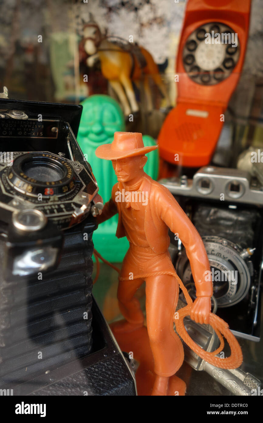 Un giocattolo di una struttura plastica cowboy, un vecchio, vintage fotocamera, un vecchio telefono arancione e un cavallo giocattolo nella finestra di Pittsburgh negozio di antiquariato Foto Stock
