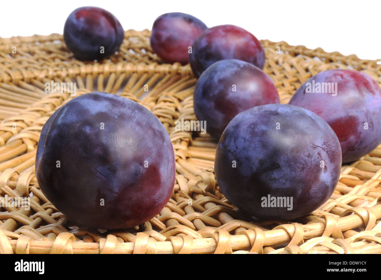 Grandi maturi prugna viola piatto di vimini. Presentato su uno sfondo bianco. Foto Stock