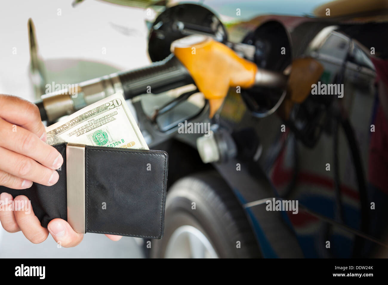 L'uomo conteggiare denaro con il rifornimento di benzina auto presso la stazione di benzina Foto Stock