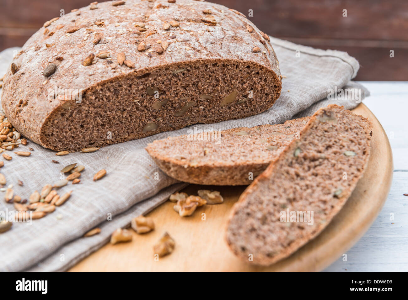 Un pane casereccio pane integrale con due fette accanto ad esso sul tavolo di legno Foto Stock
