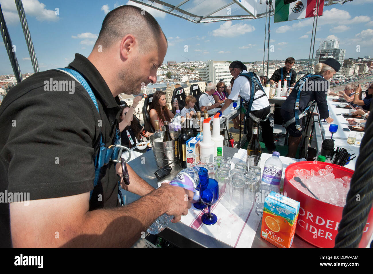 Un British Airways steward serve bevande a 22 diners a una tabella appesa a una gru, 100 piedi in alto nel cielo sopra di Brighton e Hove beach. Foto Stock