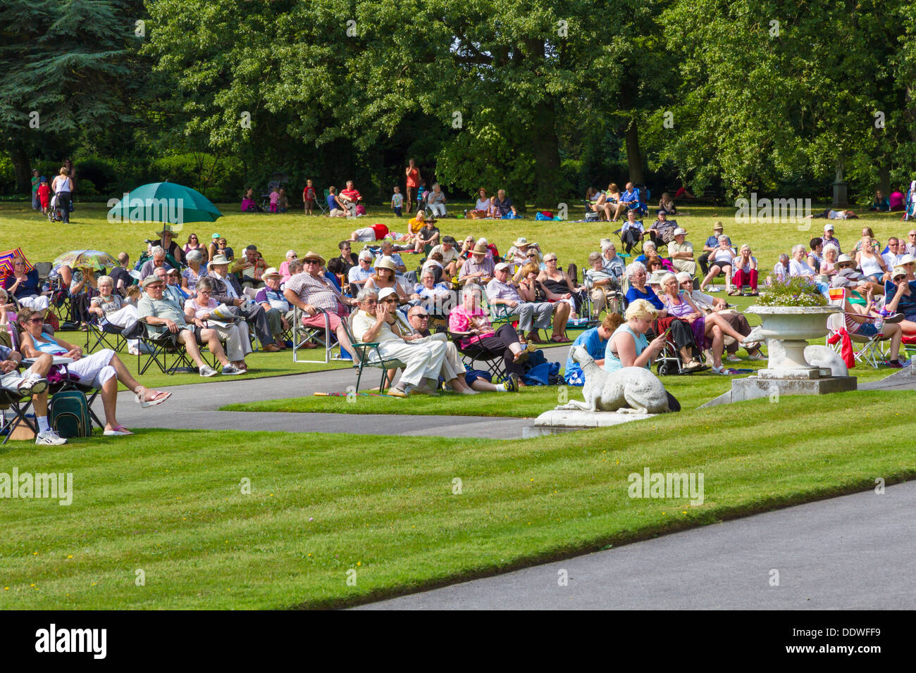 I visitatori di Brodsworth Hall di Doncaster sat sul prato sotto il sole ascolto al pomeriggio il concerto di banda. Foto Stock