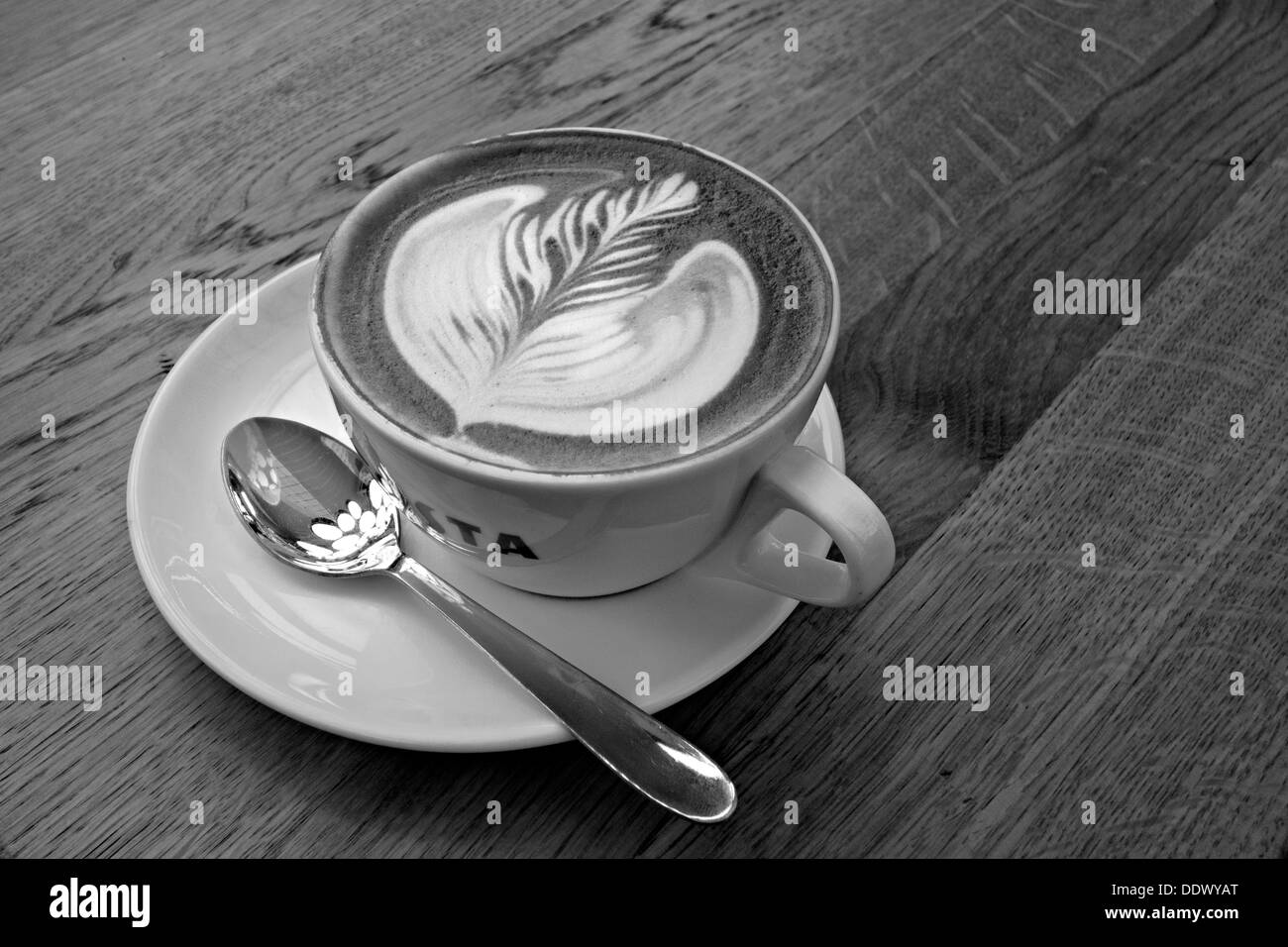 Tazza di caffè con pattern di foglia sul tavolo Foto Stock