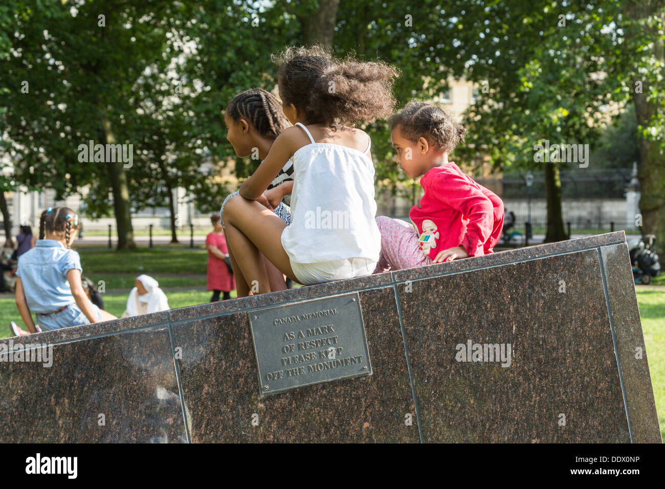 Canada Memorial, Green Park, Londra - bambini seduti sopra la placca lettura: " come un segno di rispetto si prega di mantenere spento il monumento" Foto Stock