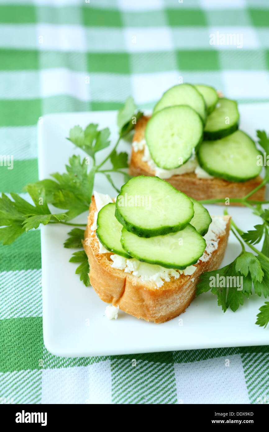 Bruschetta con formaggio e cetriolo fresco su una piastra, cibo close up Foto Stock
