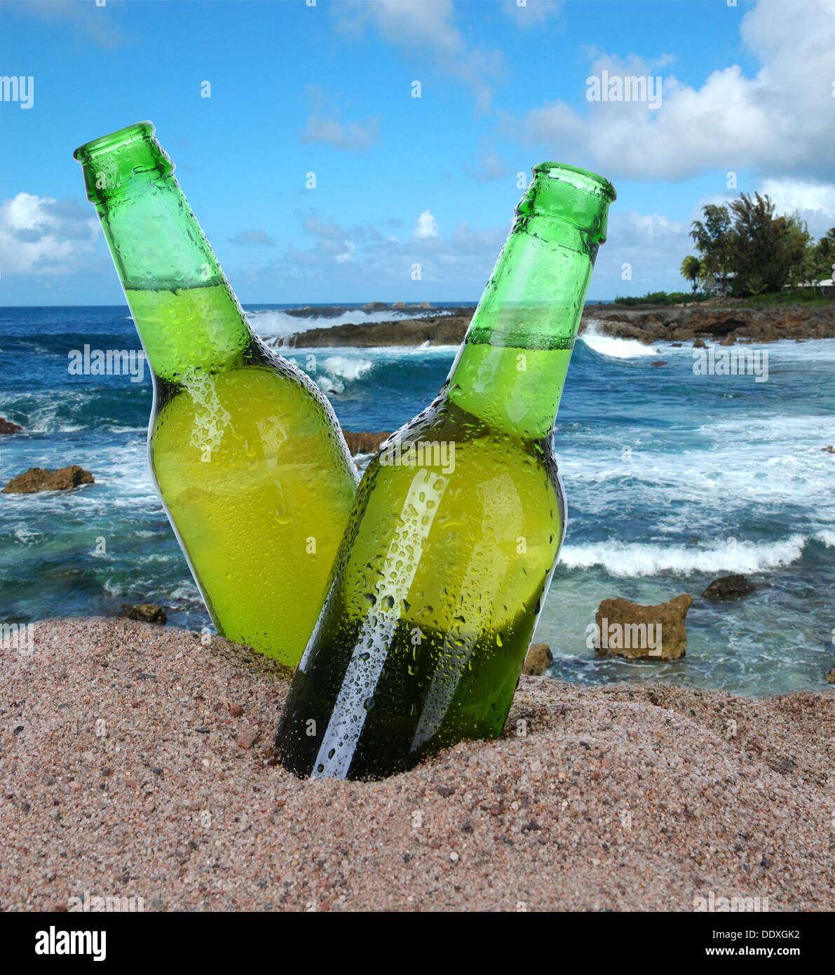 Primo piano di due bottiglie di birra nella sabbia con un oceano tropicale sfondo. Formato quadrato. I flaconi sono coperti con condensazione. Foto Stock