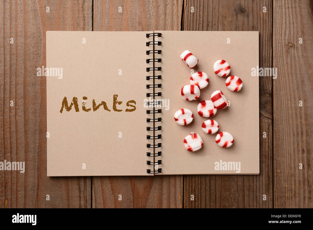Un gruppo di caramelle alla menta sulla pagina vuota di un notebook. La pagina di fronte ha la parola conia enunciato. Foto Stock