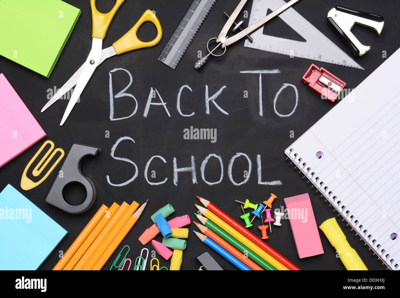 Si torna a scuola scritto su una lavagna. Le parole sono circondati da forniture scolastiche compresi, carta, forbici, matite, Foto Stock