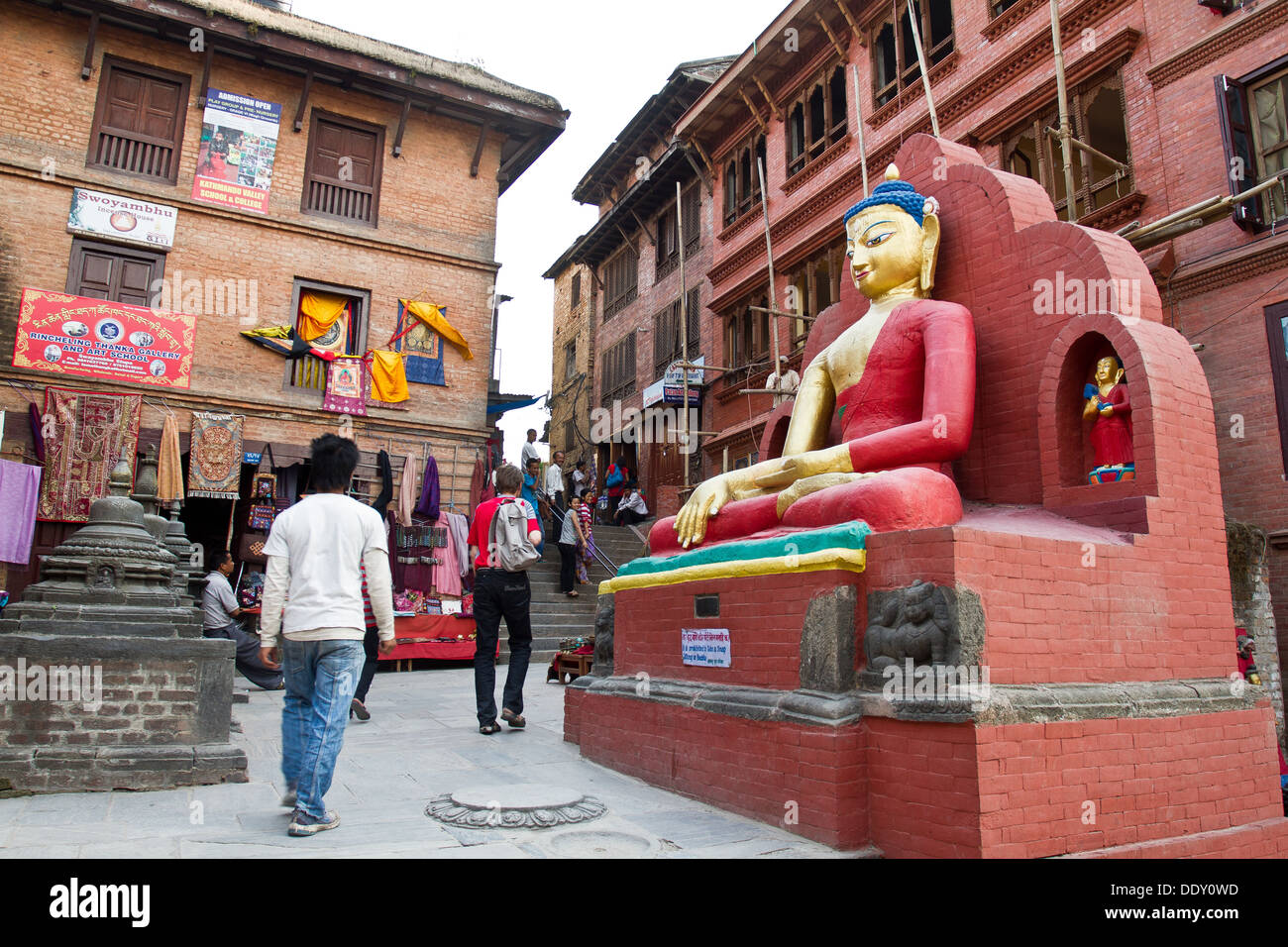 Un rosso statua del Buddha e santuario nelle strade di Kathamandu Nepal Asia Foto Stock
