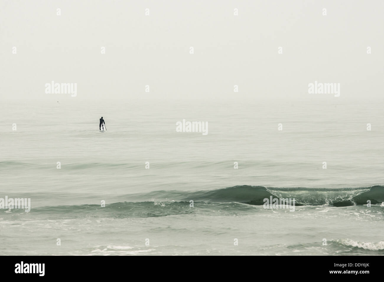 Senigallia (IT) - Inverno Foggy Seascape con un uomo immersioni su un surf. Foto Stock