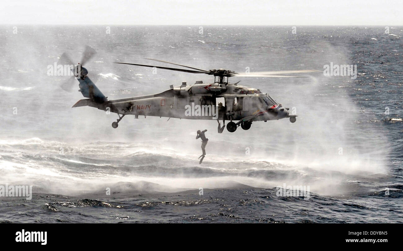 Un US Navy l'eliminazione degli ordigni esplosivi uomo salta da un MH-60S Seahawk elicottero durante una colata ed esercizio di recupero Agosto 29, 2013 nel Mare Arabico. Foto Stock
