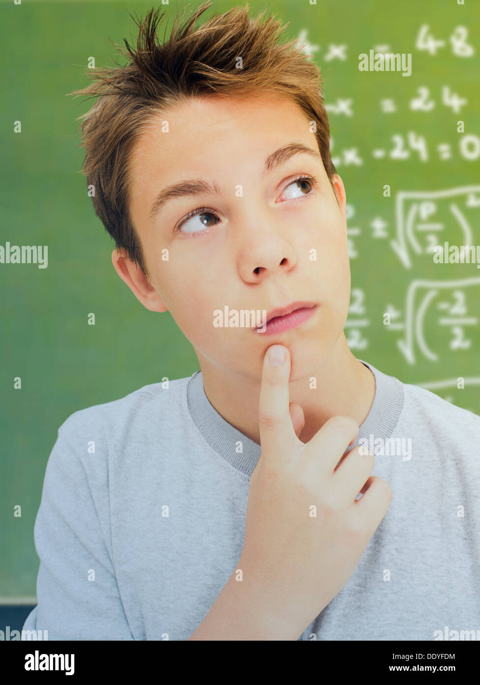 Ritratto, scolaro, adolescente, con un espressione pensosa davanti a una scuola lavagna con una equazione matematica Foto Stock