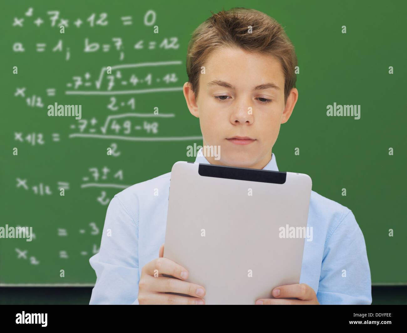Ritratto, scolaro, adolescente con un iPad davanti a una scuola lavagna con una equazione matematica Foto Stock