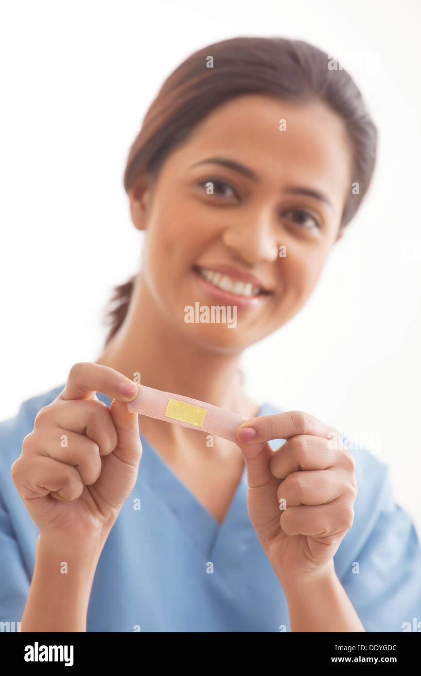 Ritratto di giovane donna chirurgo tenendo un bendaggio adesivo isolate su sfondo bianco Foto Stock