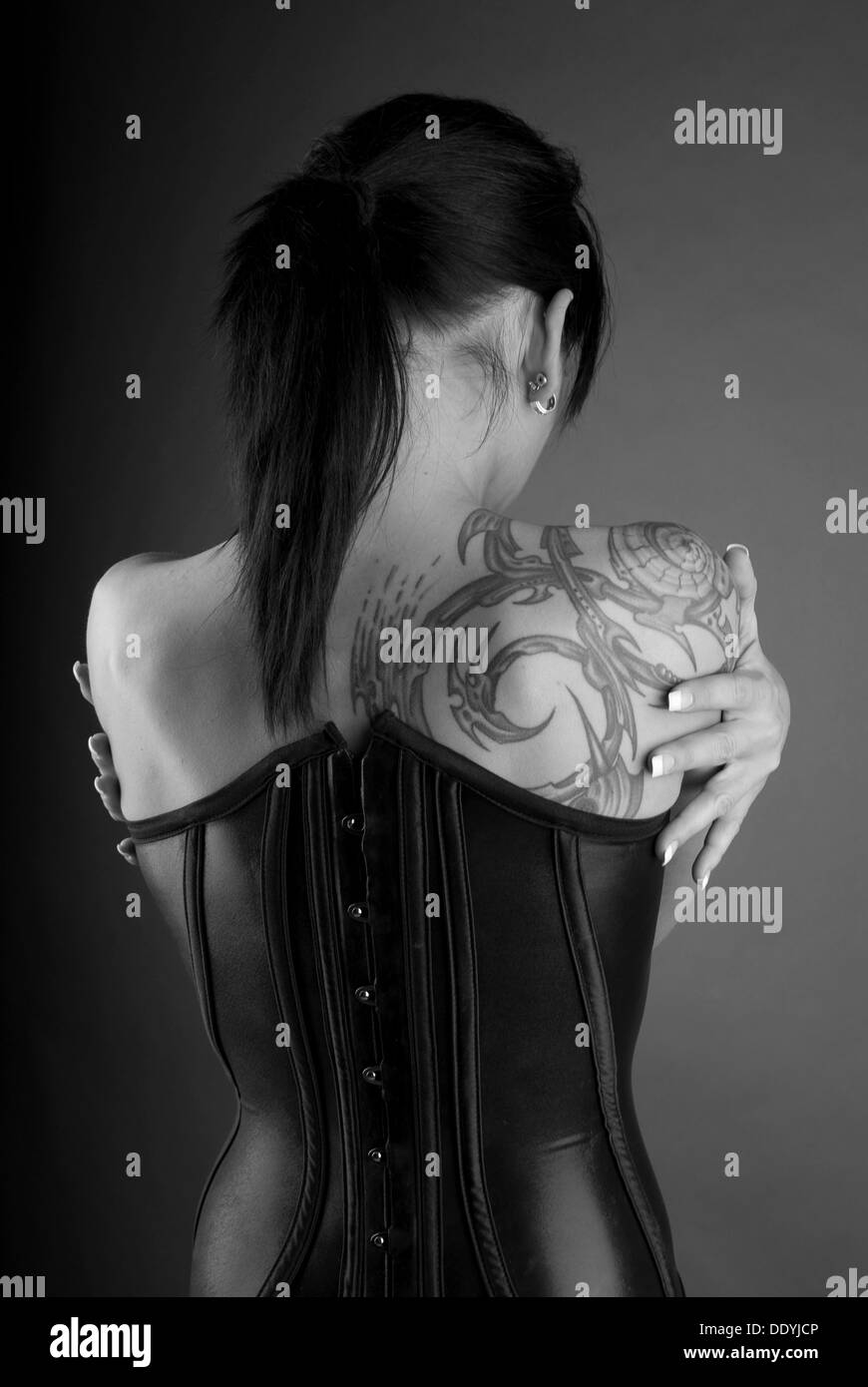 Dai capelli scuri donna vestita in un stile goth, indietro, lattice, tattoo Foto Stock