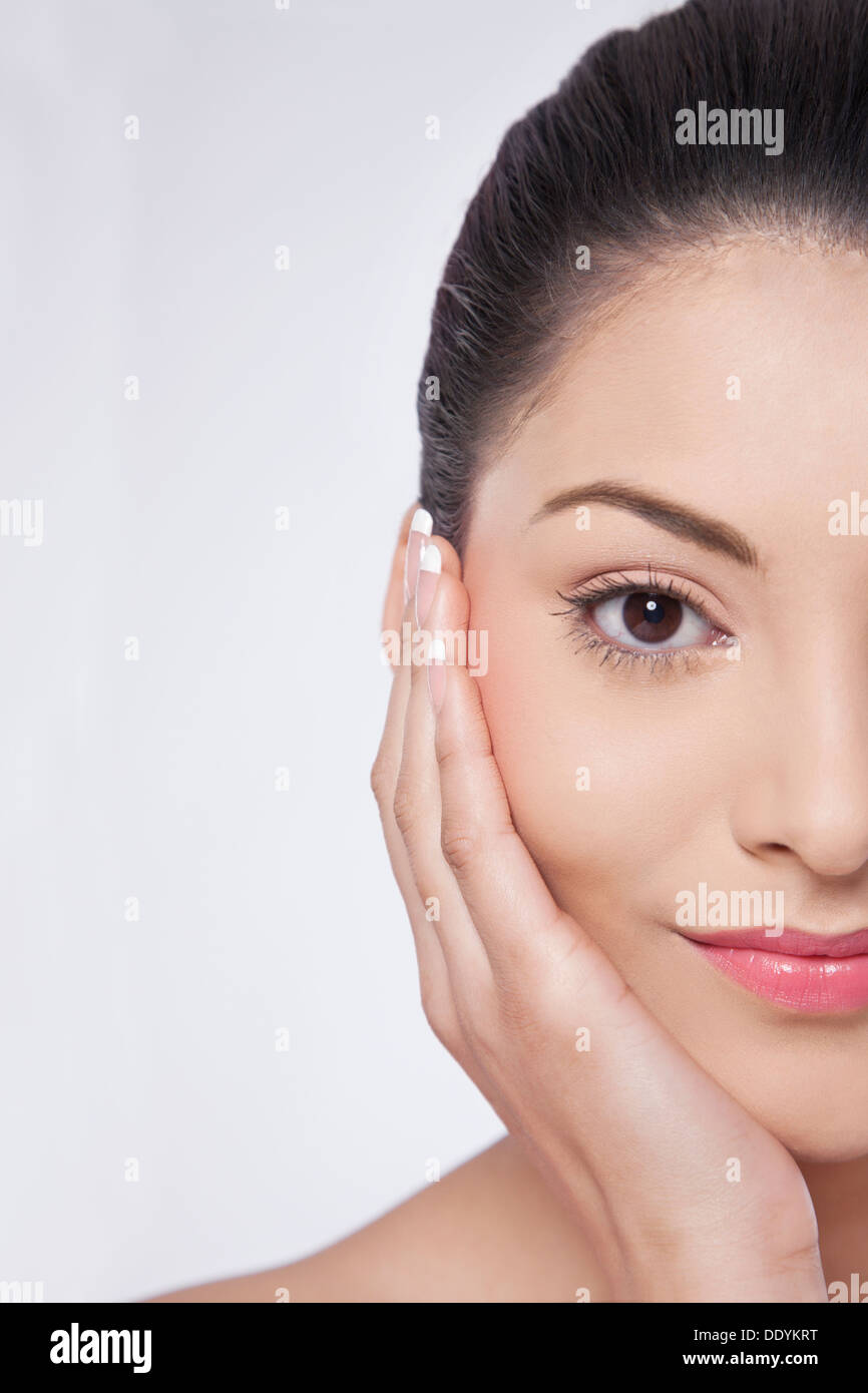 Immagine ritagliata della giovane donna di toccare la sua guance Foto Stock
