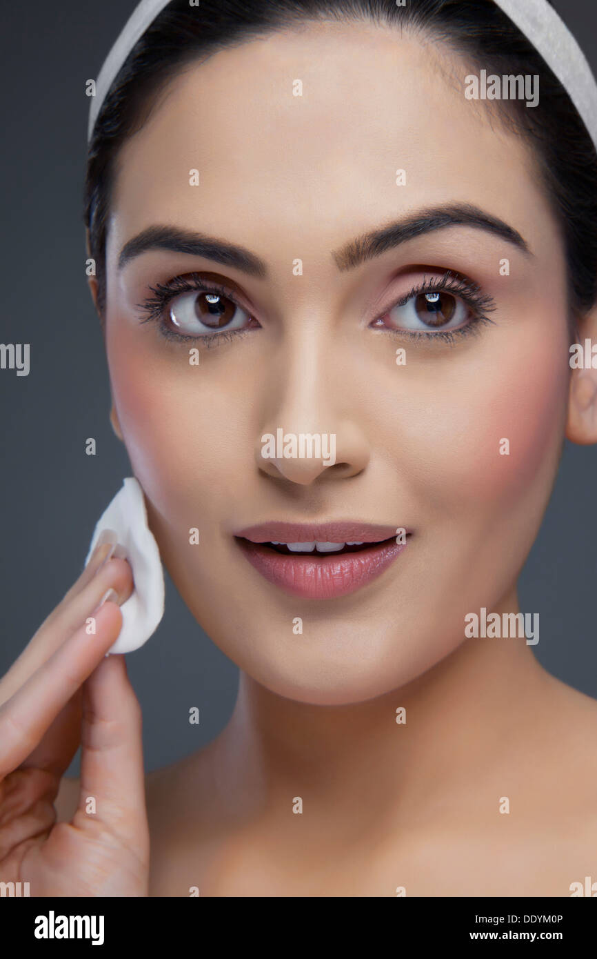 Bella giovane donna detersione viso su sfondo colorato Foto Stock