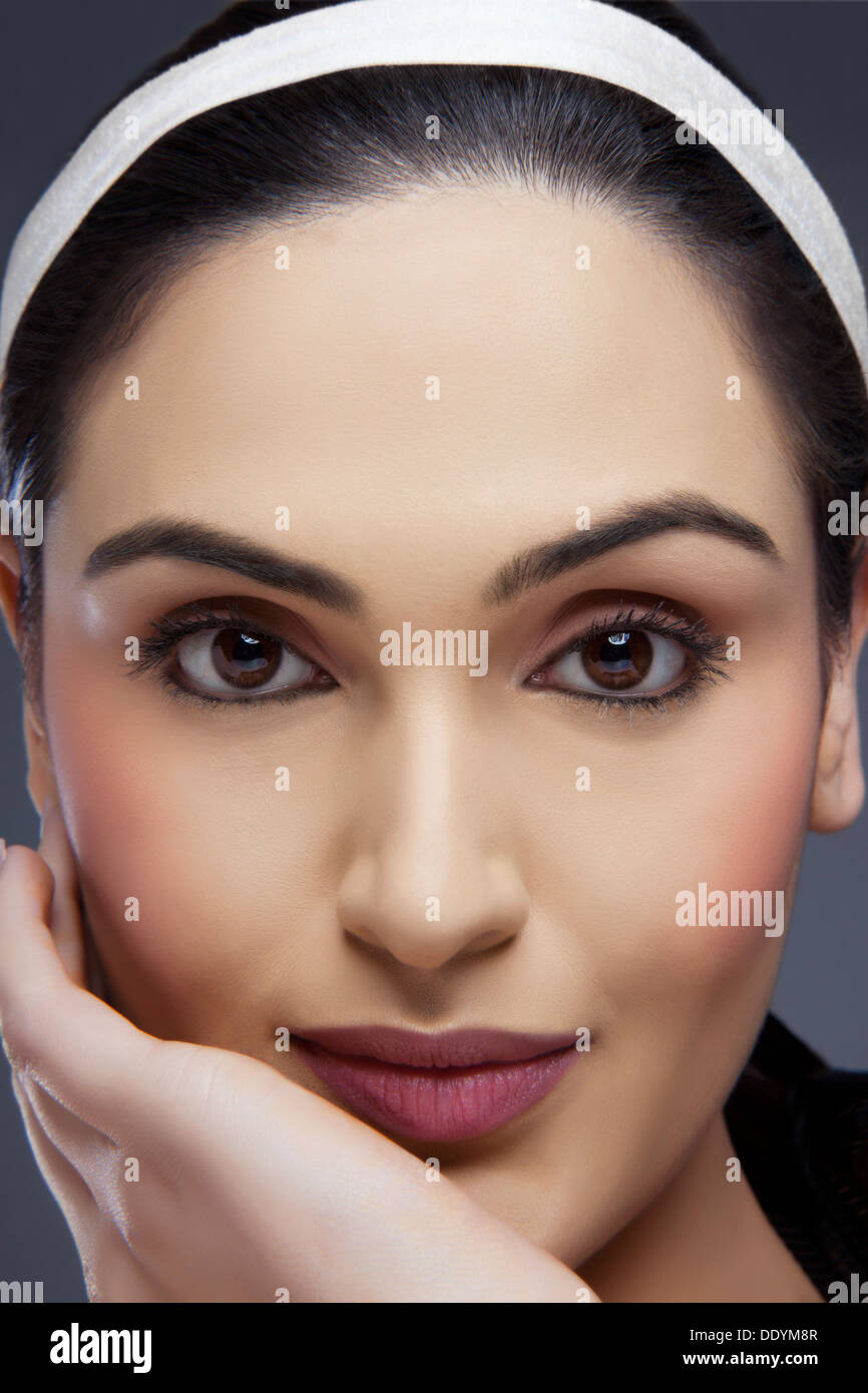 Close-up shot di una bellissima femmina con la mano sulla sua faccia su sfondo colorato Foto Stock