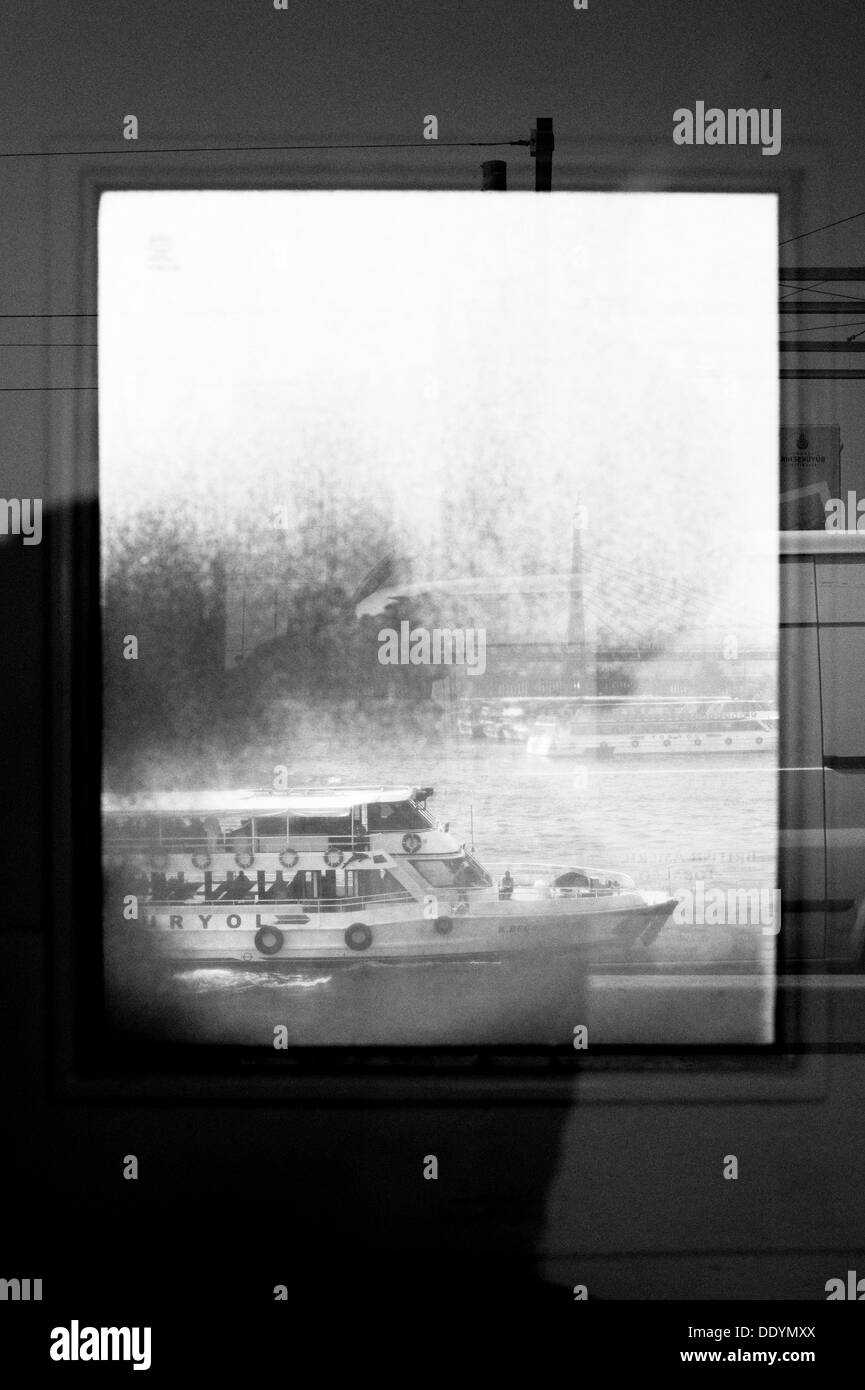 Una barca di crociera sul Fiume Bosphorus Istanbul. Essa è stata presa attraverso una finestra sporca che ha fornito una cornice all'interno di un telaio. Foto Stock