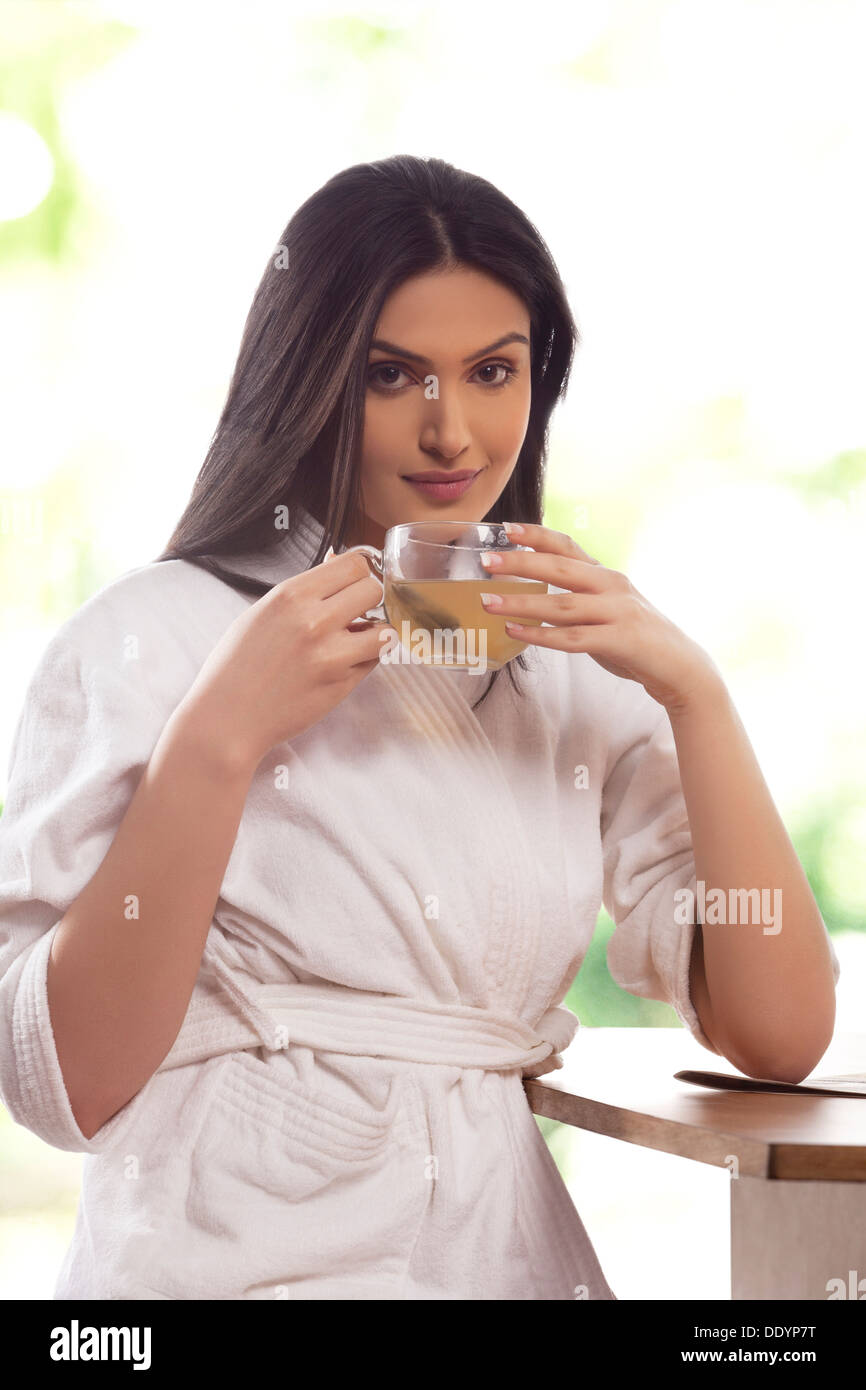 Ritratto di felice giovane donna in accappatoio bere il tè Foto Stock