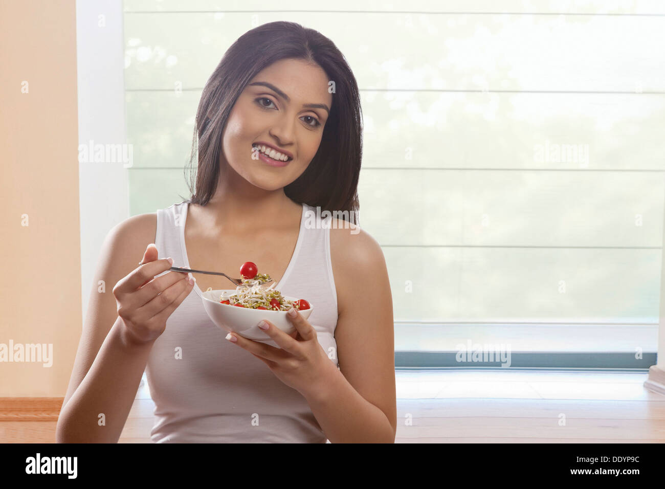 Ritratto di felice giovane donna di mangiare i germogli di soia e di pomodori ciliegini Foto Stock