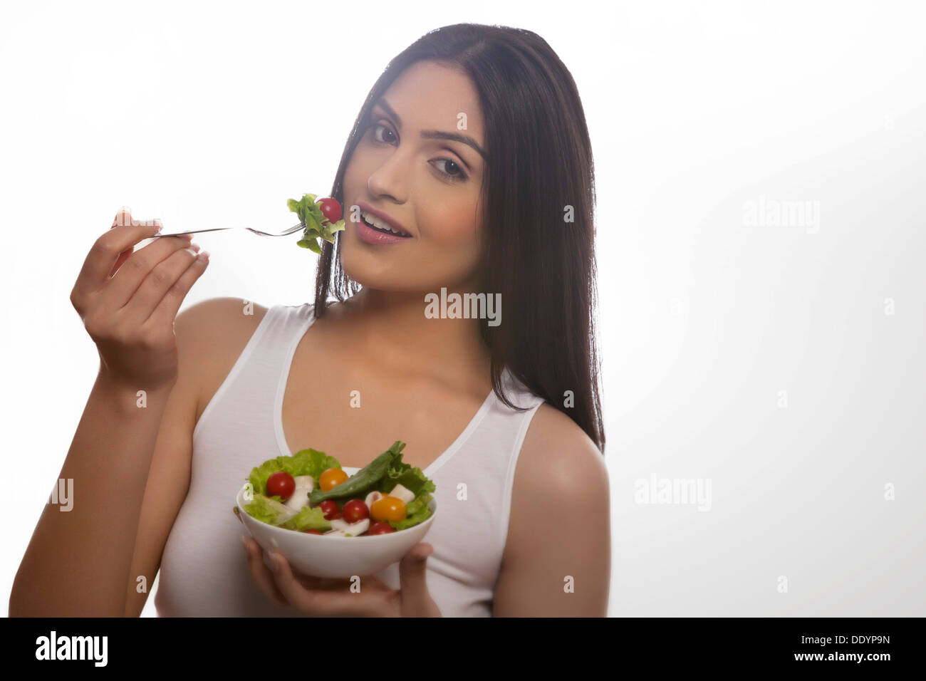 Ritratto di felice giovane donna di mangiare insalata di lattuga, pomodori ciliegini e funghi Foto Stock