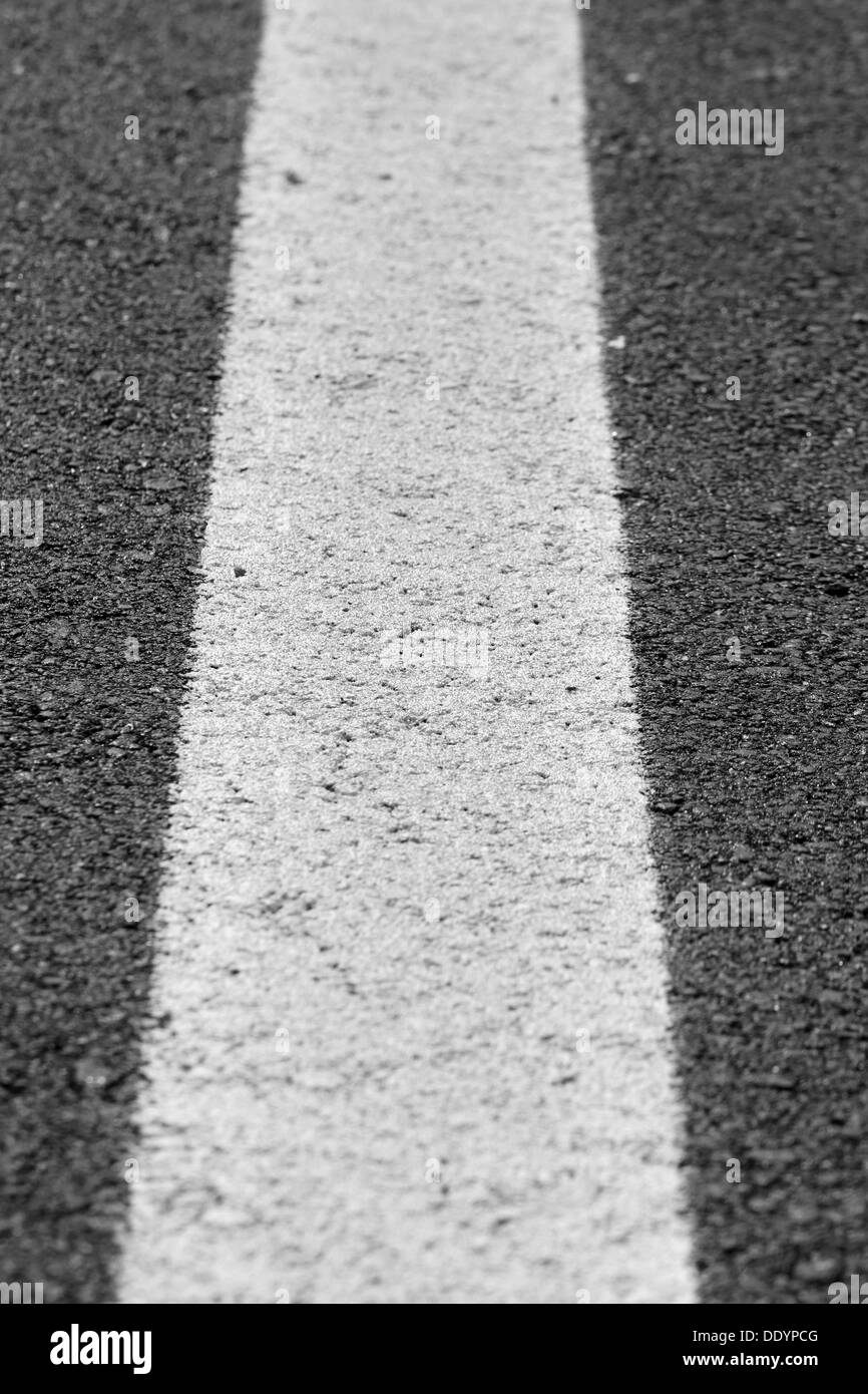 Riga bianca verticale dipinta attraverso il nero asfalto Foto Stock