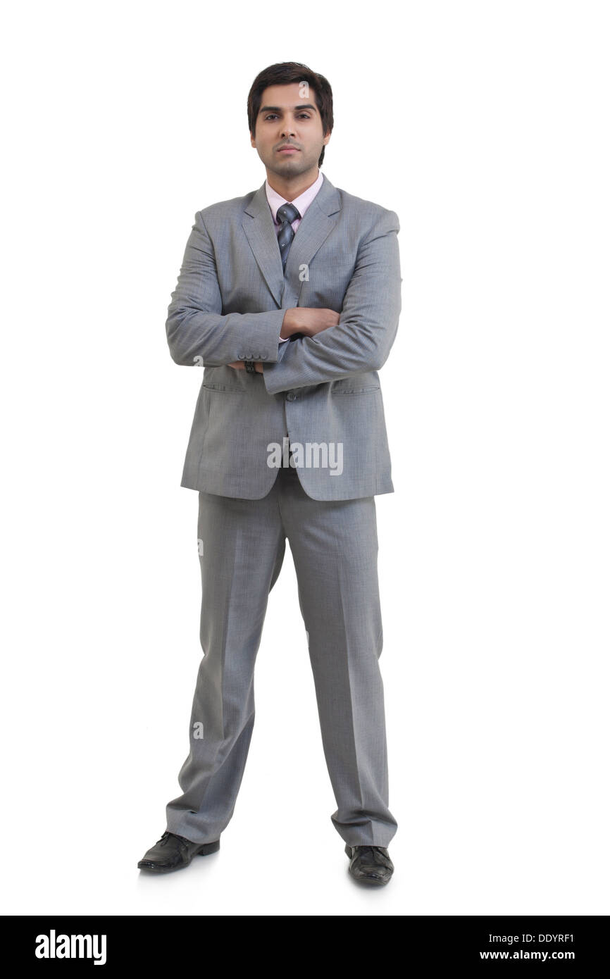 A piena lunghezza Ritratto di fiducioso imprenditore con le braccia incrociate in piedi contro uno sfondo bianco Foto Stock