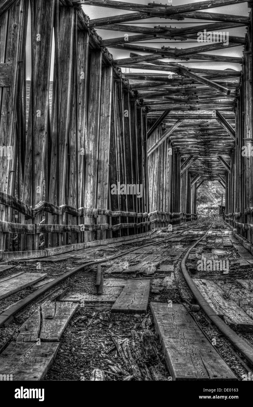 Drammatico, in legno antico ponte ferroviario attraversamento Red Deer river, è stata utilizzata per spostare il carbone. Decadimento e abbandonate e arrugginite rotaie. B&W HDR Foto Stock