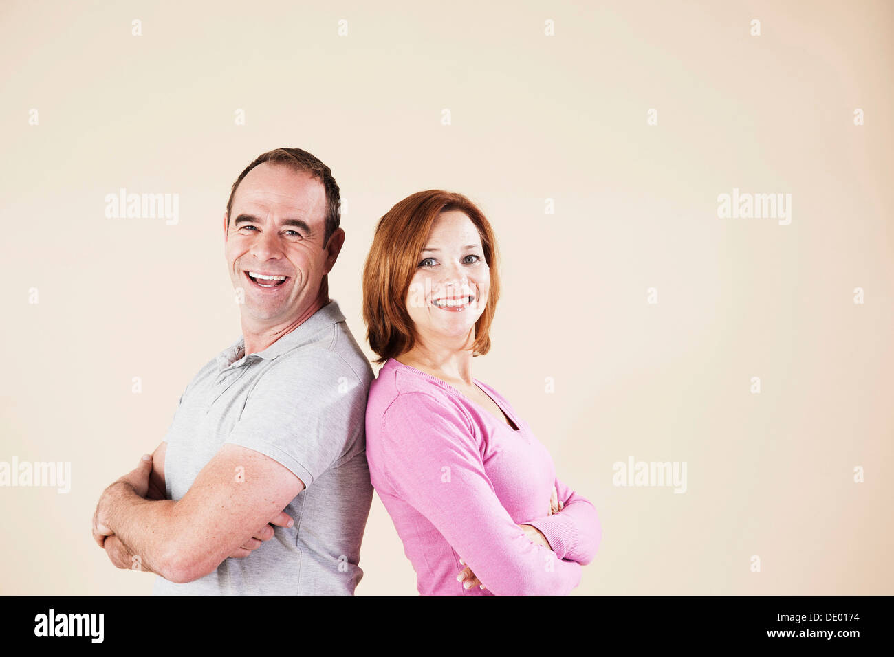 Coppia sorridente, spalle dorso a dorso Foto Stock