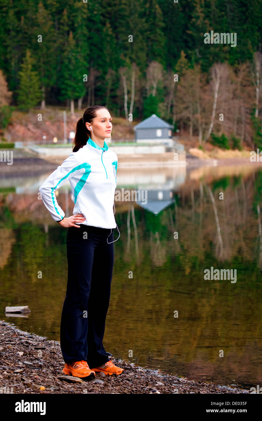 Giovane donna in fase di riscaldamento per fare jogging a una foresta lago Foto Stock