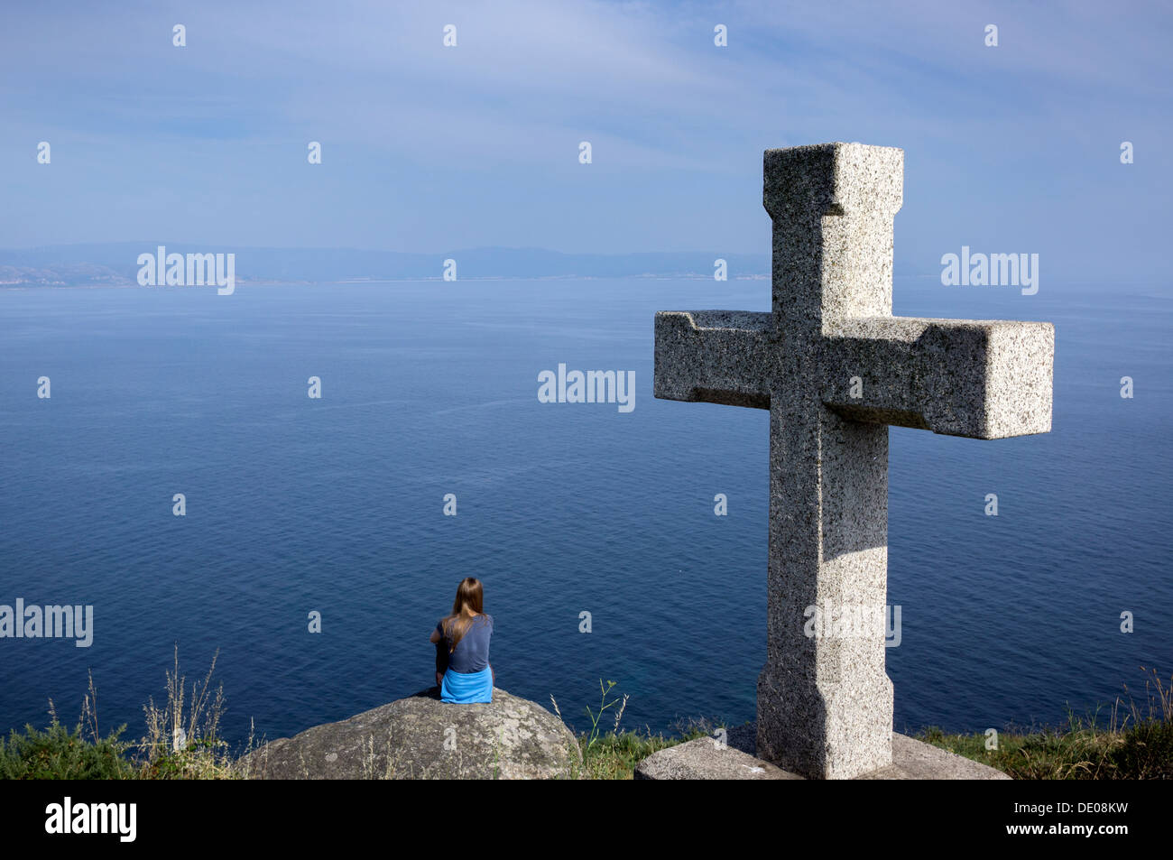 Un turista si trova sulle scogliere vicino al faro di Finisterre, la fine di un tratto del cammino di san Giacomo. Foto Stock