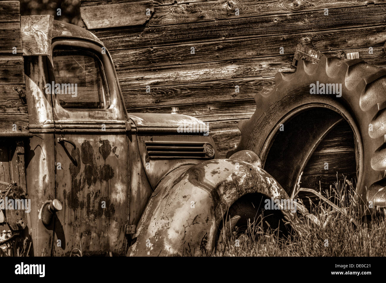Ambientazione rurale del vecchio rustico, antica fattoria, carrello, seduto di fronte a un vecchio granaio o capannone, il pneumatico del trattore in background. Foto Stock