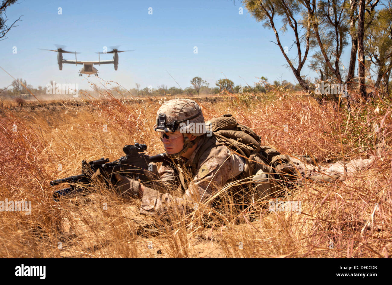US Marine Corps Lance Cpl. Giovanni pronto fornisce la sicurezza come una MV-22 Osprey tiltrotor aereo decolla dopo inserimento di un plotone di marines durante un sistema integrato di live-fire esercizio presso il campo Bradshaw Area Formazione 3 settembre 2013 nel Territorio del Nord, l'Australia. Foto Stock