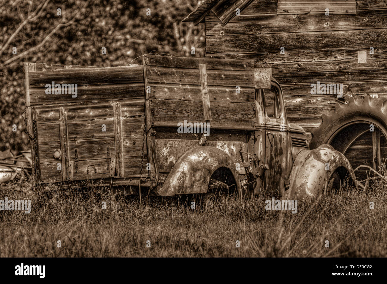 Ambientazione rurale del vecchio rustico, antica fattoria, carrello, seduto di fronte a un vecchio granaio o capannone, il pneumatico del trattore in background. Foto Stock