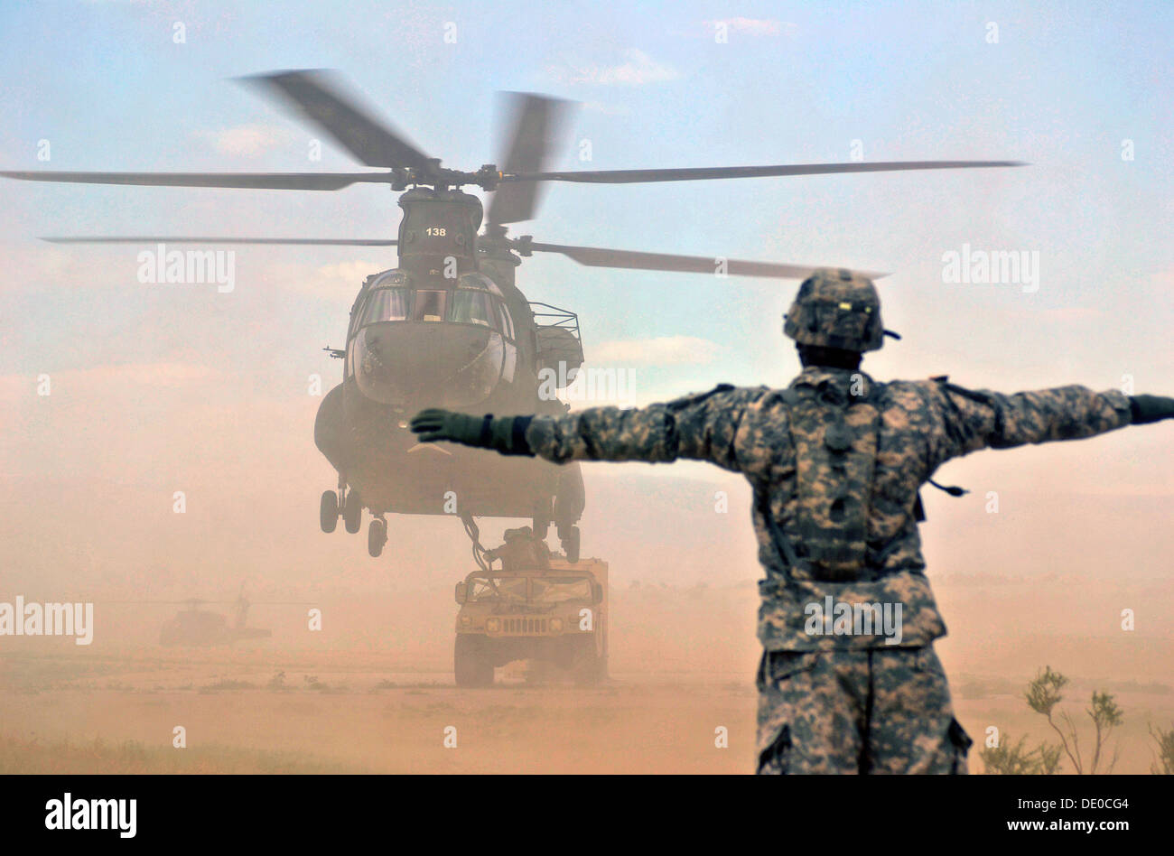Un U.S. Soldato dirige un CH-47 Chinook pilota di elicottero mentre i soldati con la decima delle forze speciali Gruppo fissare un Humvee da imbracare-caricati durante una formazione sul campo esercizio luglio 25, 2013 vicino a Fort Carson, CO. Foto Stock
