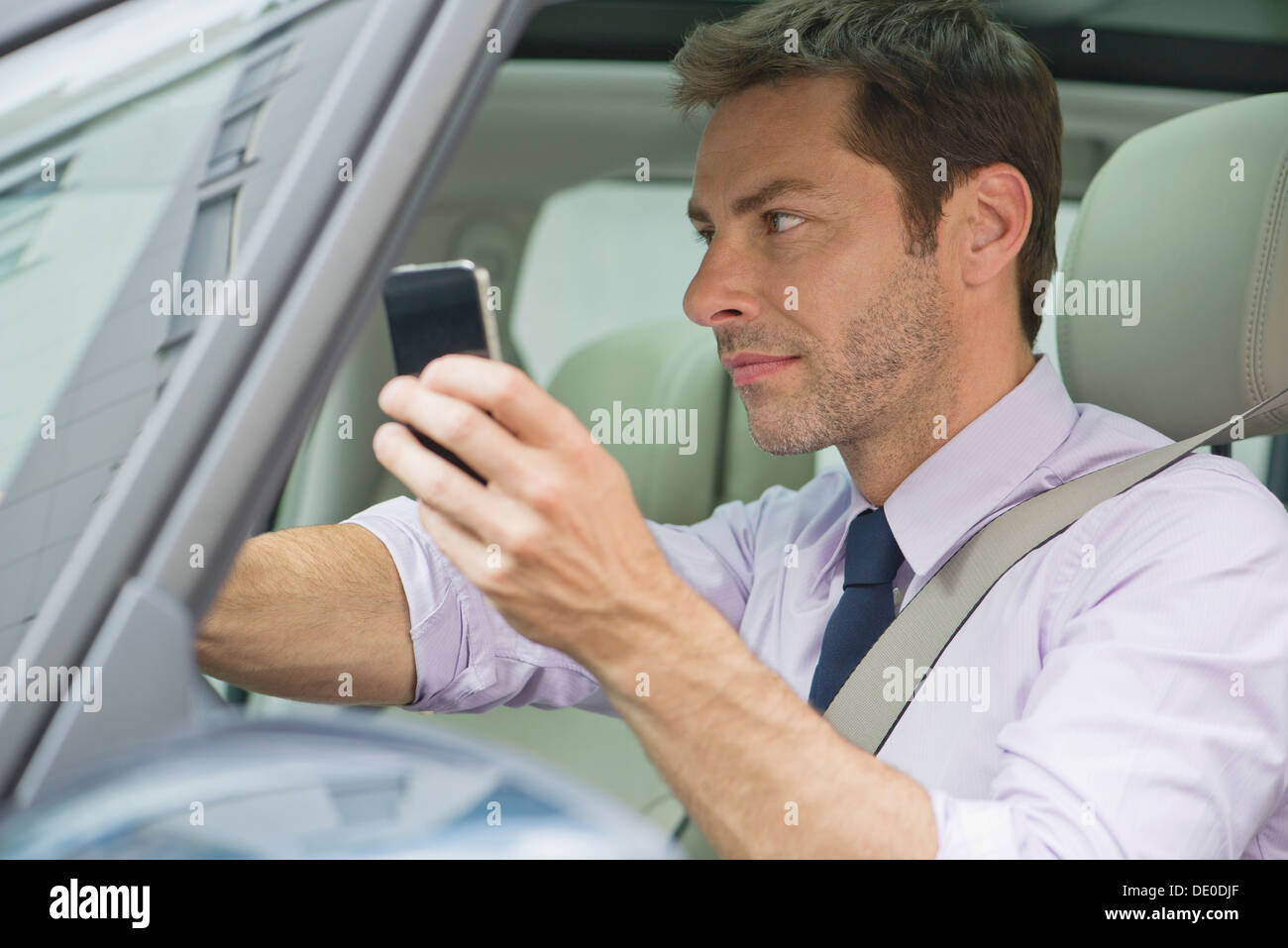 L'uomo utilizza lo smartphone durante la guida Foto Stock