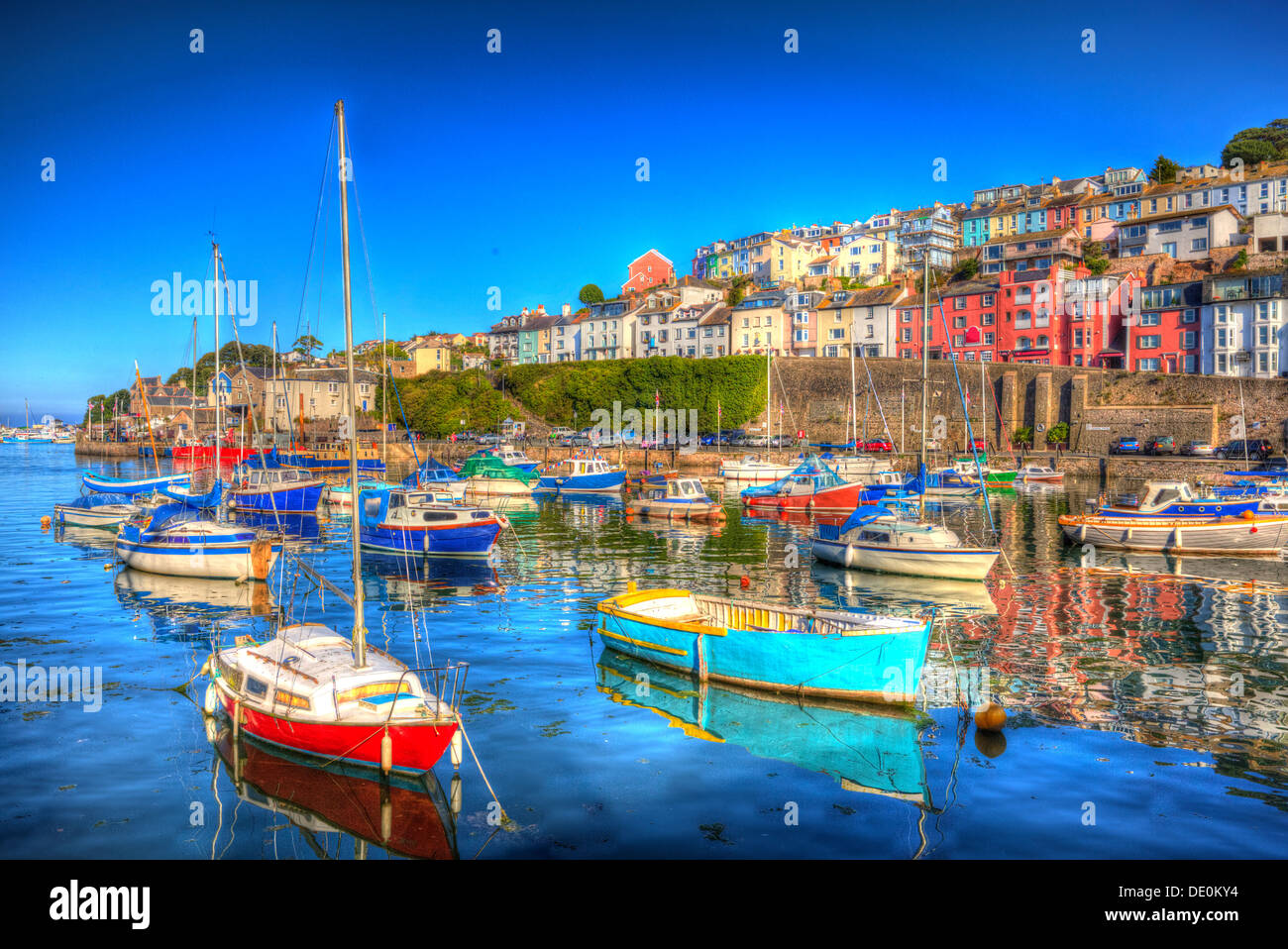 Colori brillanti per barche di rosso verde turchese con il blu del cielo e del mare a brixham devon in HDR con case sulla collina Foto Stock