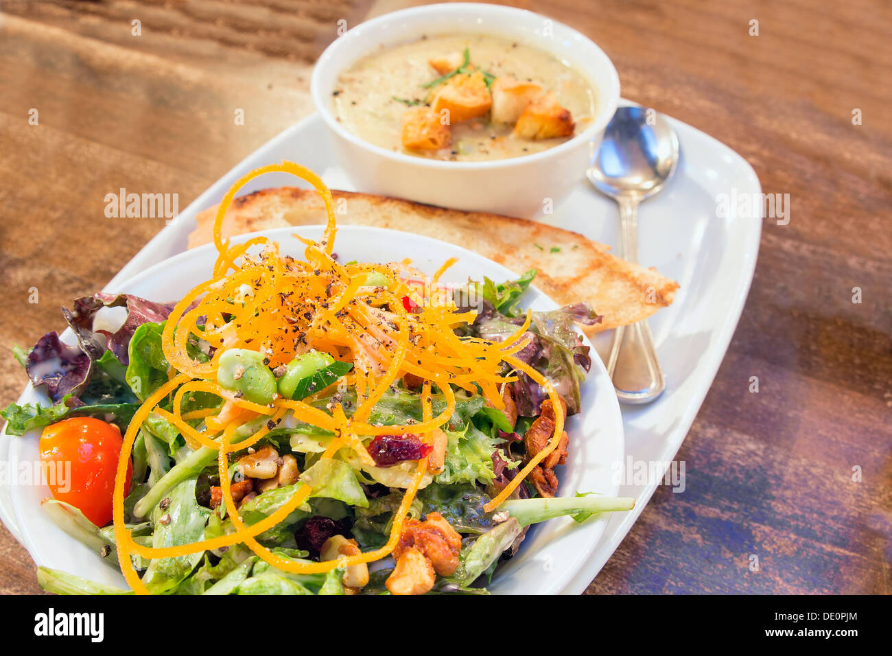 Verde primavera con insalata di pomodoro Edamame anacardi mirtilli rossi e una ciotola di zuppa di mais zuppa Closeup Foto Stock