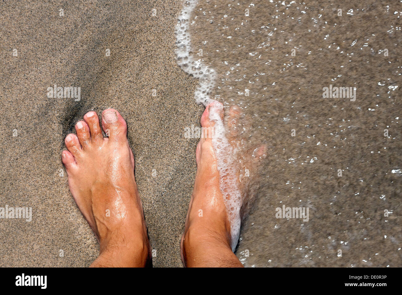 I piedi su una spiaggia, essendo lambite dal mare Foto Stock