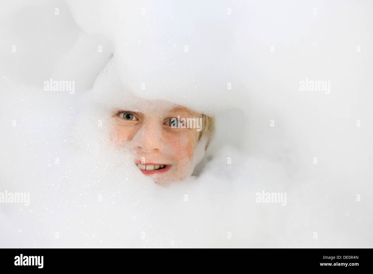 Il ragazzo, 9 anni, capo immerso nel bagno di schiuma Foto Stock