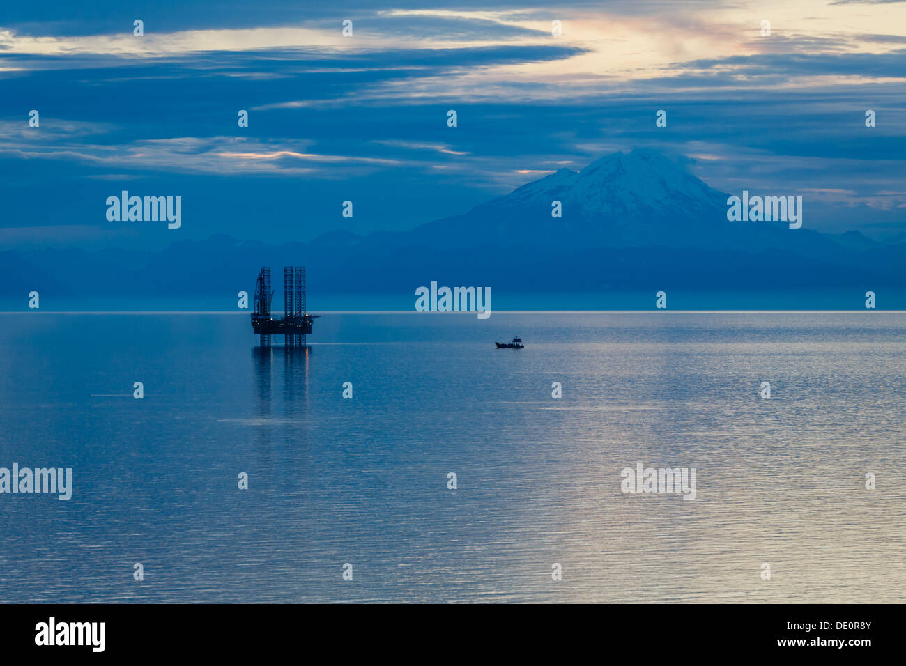 Il petrolio e il gas platform riflettendo sull'acqua nella Insenatura Cook , Alaska, con montagne innevate sullo sfondo Foto Stock