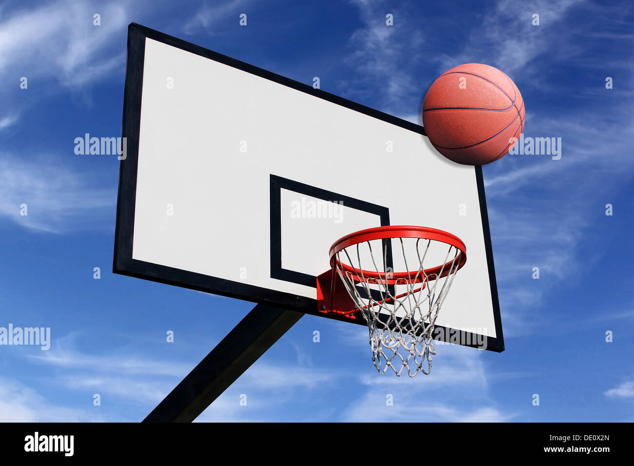 Una palla da basket e un pannello di pallacanestro su uno sfondo di cielo  blu Foto stock - Alamy
