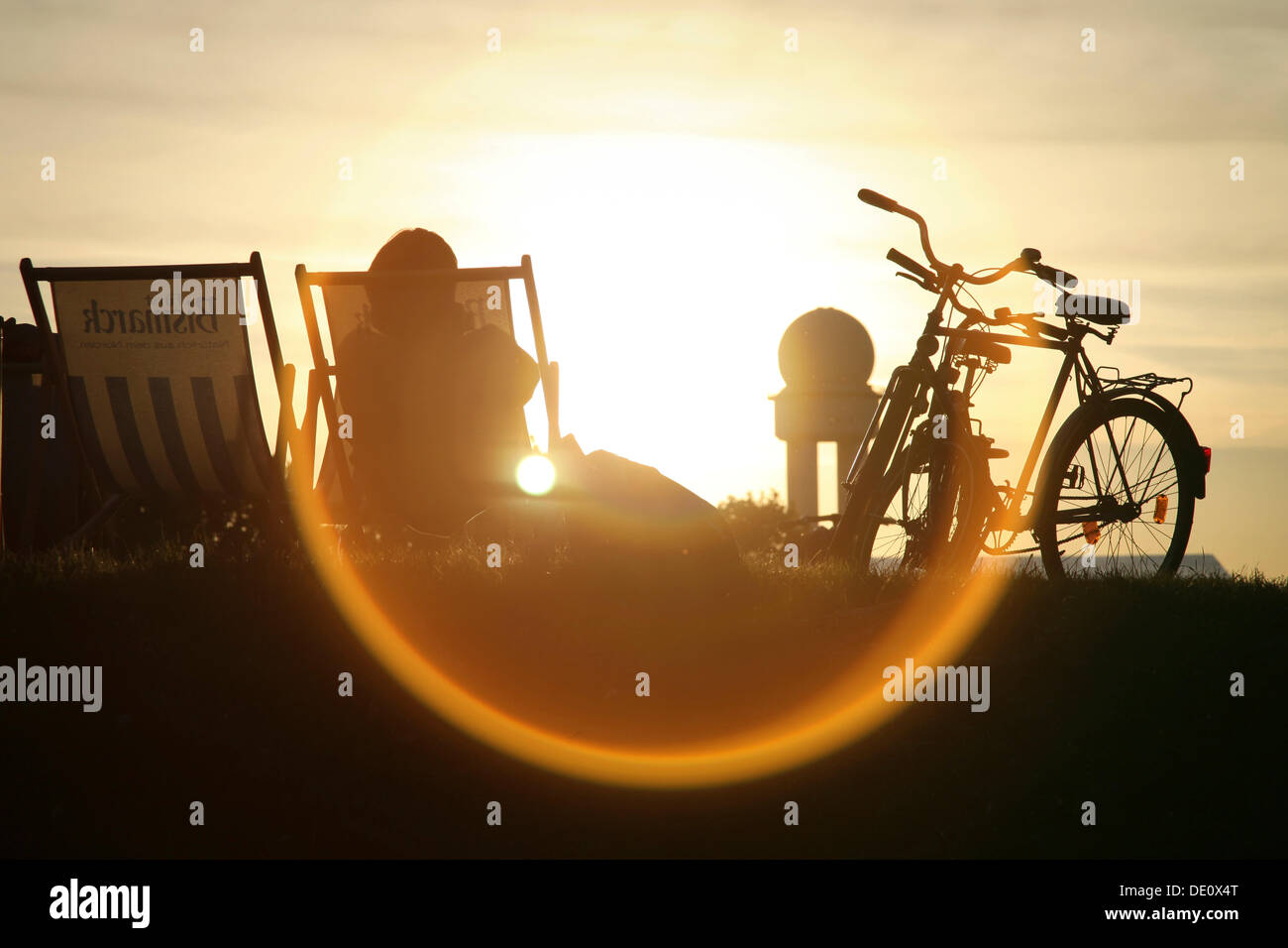 Persona seduta su una sedia a sdraio, retro illuminato, in un parco pubblico a motivo dell'ex Berlino Tempelhof di Berlino Foto Stock