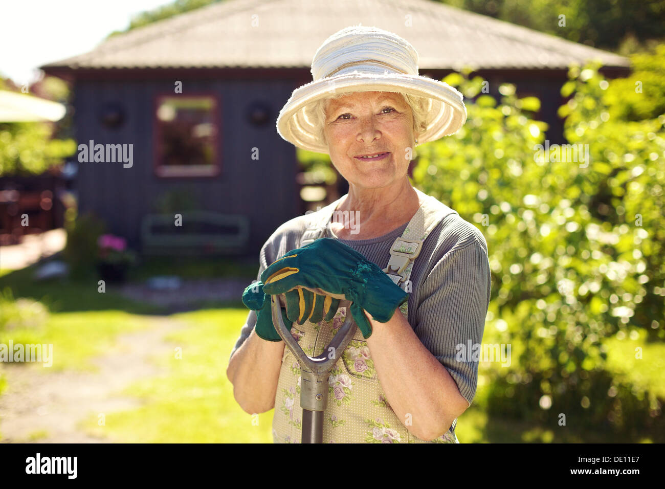 Ritratto di donna di sambuco con utensili da giardinaggio all'esterno. Senior donna in piedi con la pala nel suo cortile Foto Stock