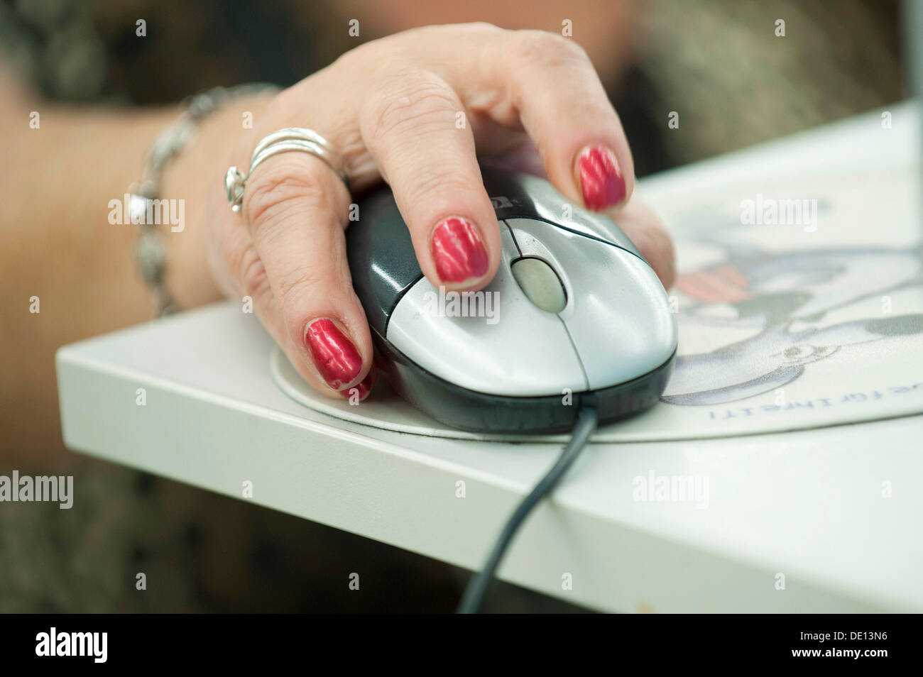 La mano di una donna anziana operando un mouse del computer Foto Stock